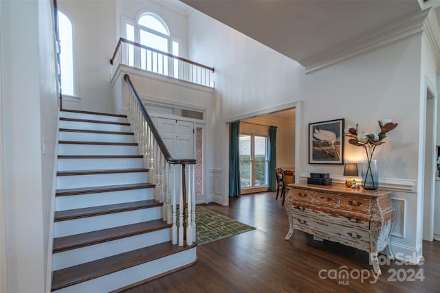 foyer featuring a high ceiling, crown molding, a healthy amount of sunlight, and dark hardwood / wood-style flooring