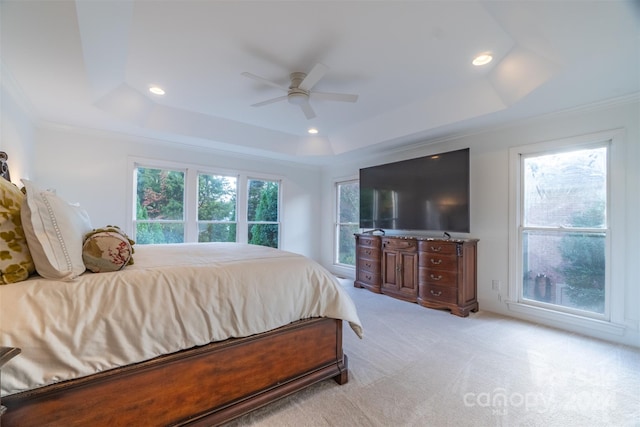 carpeted bedroom with a tray ceiling, ceiling fan, and ornamental molding