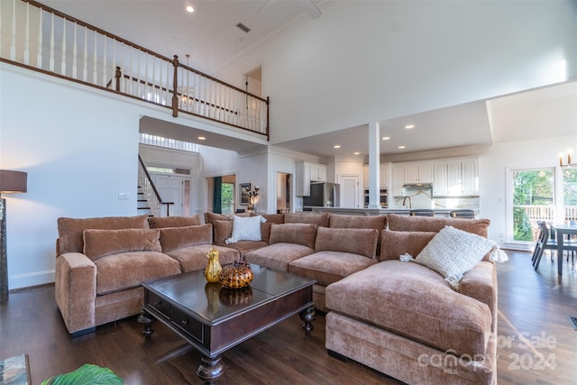 living room with crown molding, dark hardwood / wood-style flooring, and a towering ceiling