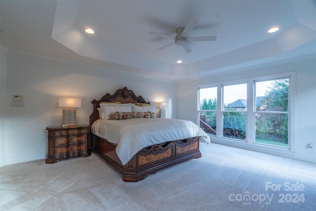 bedroom with ornamental molding, a tray ceiling, ceiling fan, and light colored carpet