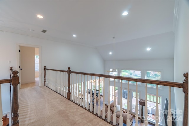 hall featuring ornamental molding, lofted ceiling, and light carpet