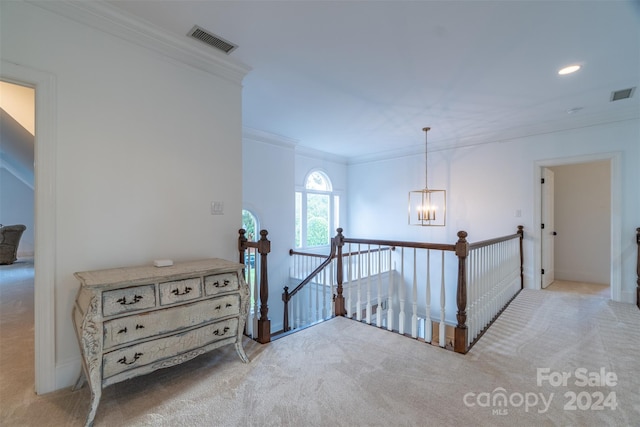 hall with light colored carpet, an inviting chandelier, and crown molding