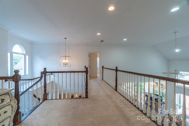 hall featuring light carpet, a chandelier, vaulted ceiling, and ornamental molding