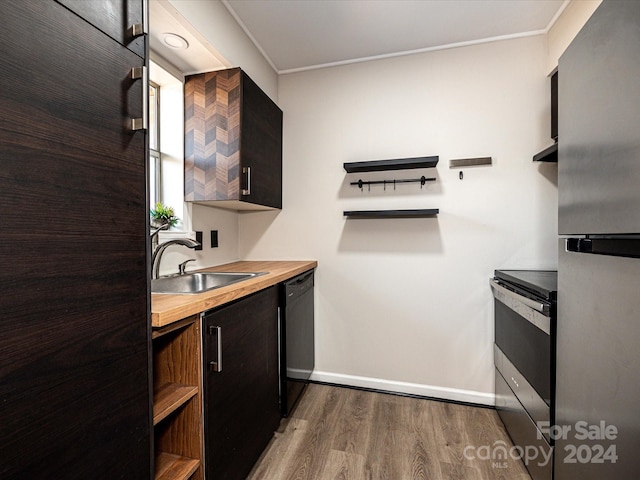 kitchen with butcher block counters, light hardwood / wood-style floors, sink, appliances with stainless steel finishes, and crown molding