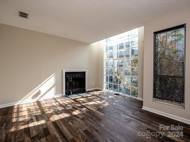 unfurnished living room featuring a textured ceiling and dark hardwood / wood-style flooring