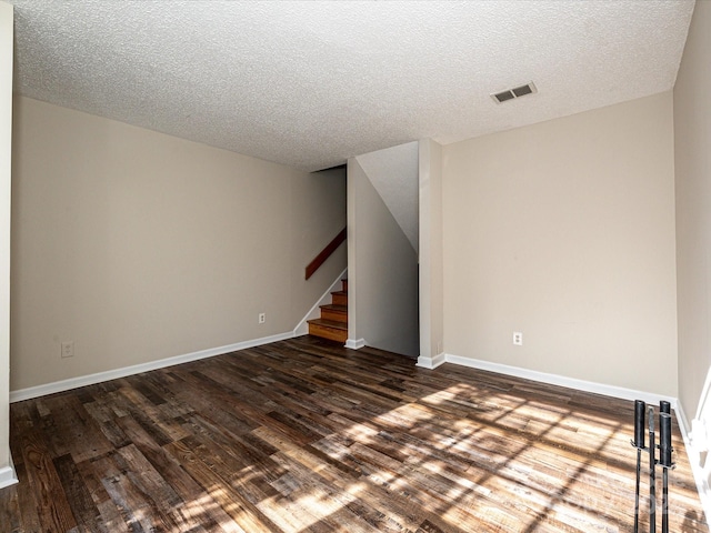 unfurnished room featuring dark wood-type flooring and a textured ceiling