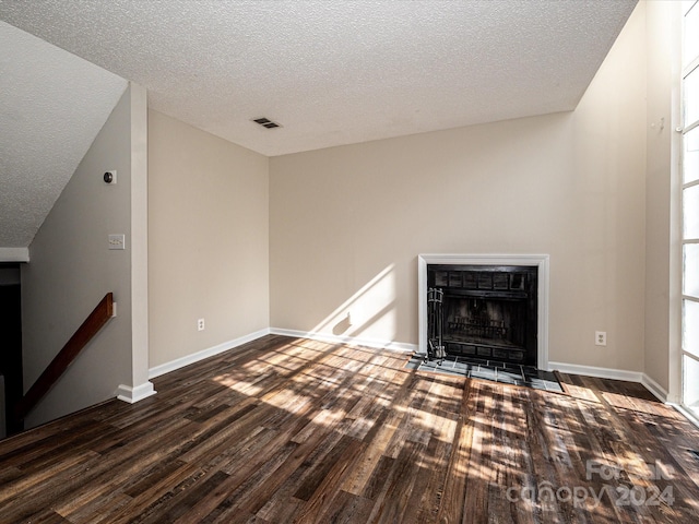 unfurnished living room featuring dark wood-type flooring and a textured ceiling