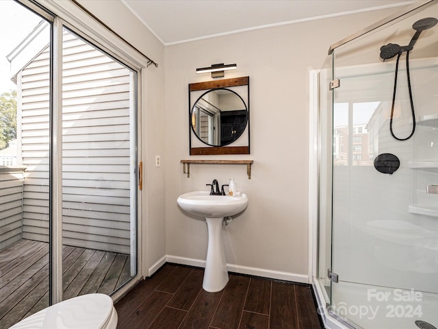 bathroom with toilet, hardwood / wood-style flooring, crown molding, and a shower with shower door