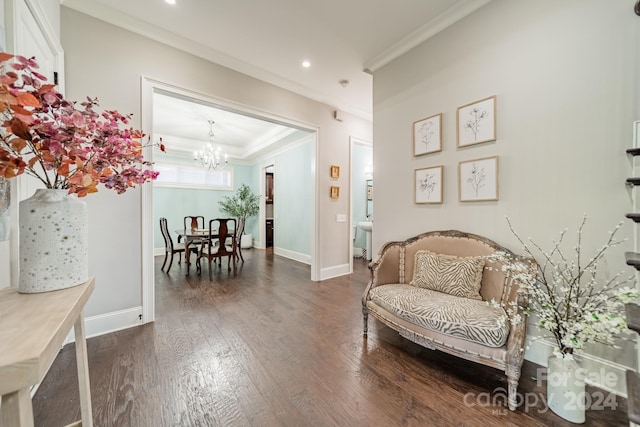 sitting room with ornamental molding, dark wood-type flooring, and a notable chandelier