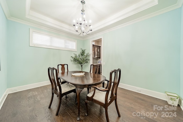 dining space with ornamental molding, a raised ceiling, dark hardwood / wood-style flooring, and an inviting chandelier