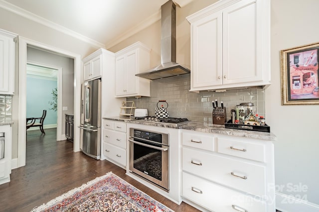 kitchen featuring wall chimney exhaust hood, dark wood-type flooring, light stone counters, white cabinets, and appliances with stainless steel finishes