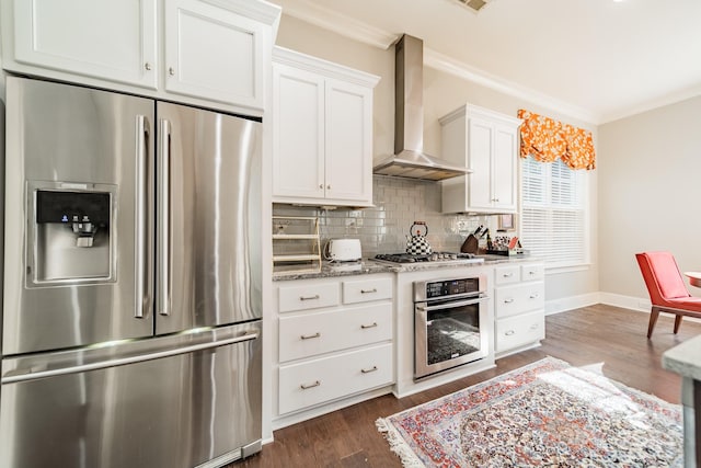 kitchen with white cabinetry, crown molding, wall chimney range hood, and appliances with stainless steel finishes