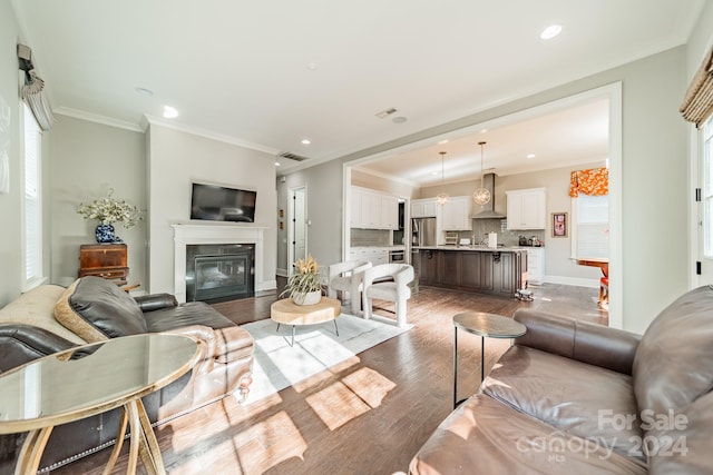 living room featuring a wealth of natural light, crown molding, and wood-type flooring