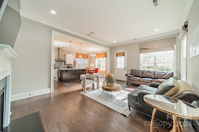 living room featuring an inviting chandelier, dark hardwood / wood-style floors, and ornamental molding