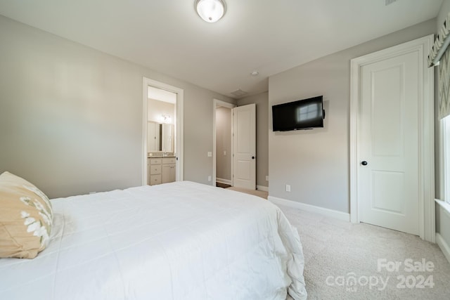 bedroom with ensuite bath and light carpet