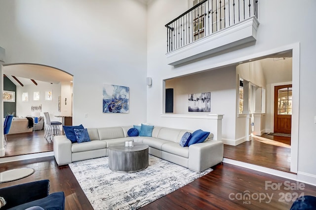 living room with a towering ceiling and dark hardwood / wood-style floors