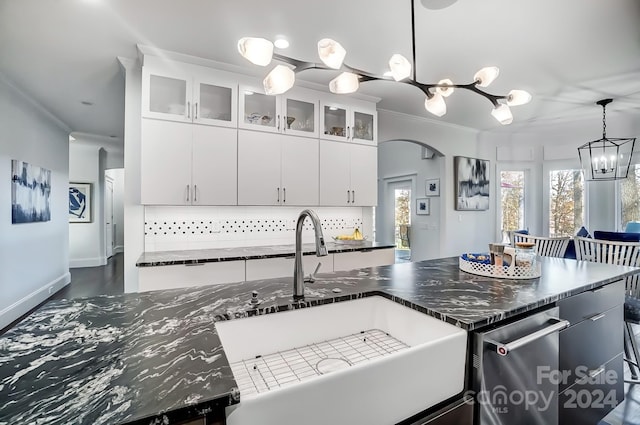 kitchen with backsplash, a kitchen island with sink, white cabinets, and pendant lighting