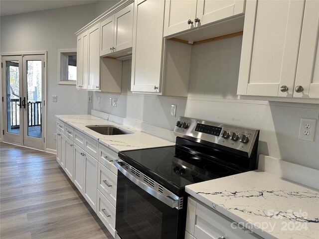 kitchen featuring french doors, light stone counters, light hardwood / wood-style floors, stainless steel electric stove, and white cabinets