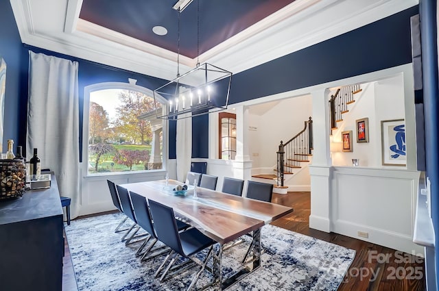 dining space featuring crown molding, stairs, wood finished floors, an inviting chandelier, and a raised ceiling