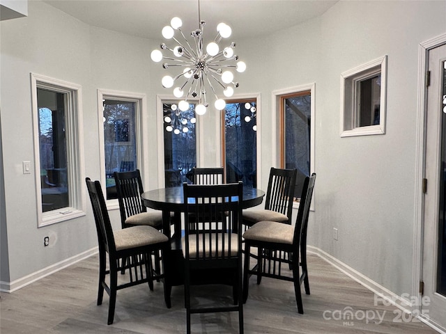 dining space featuring a chandelier, wood finished floors, and baseboards