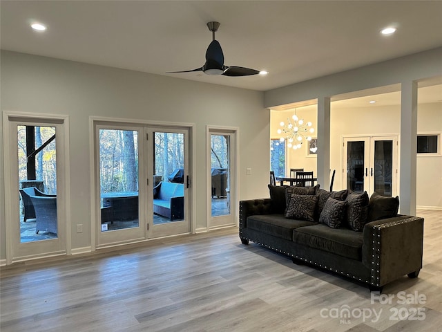 living room with ceiling fan with notable chandelier, baseboards, wood finished floors, and recessed lighting