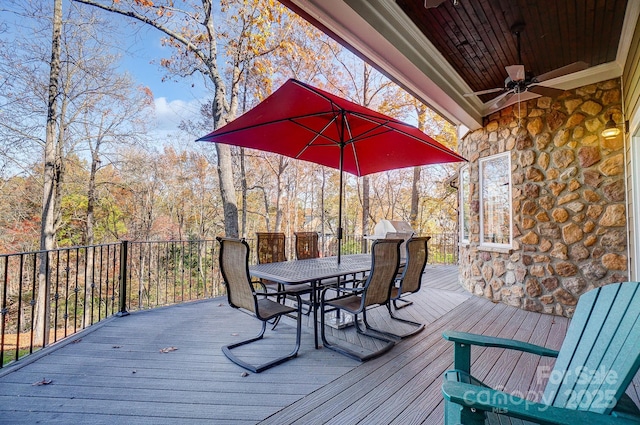 wooden deck featuring outdoor dining space and a ceiling fan