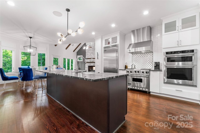 20361 Enclave Oaks Ct, Cornelius, NC 28031 - kitchen featuring premium appliances, wall chimney exhaust hood, a kitchen bar, backsplash, and pendant lighting