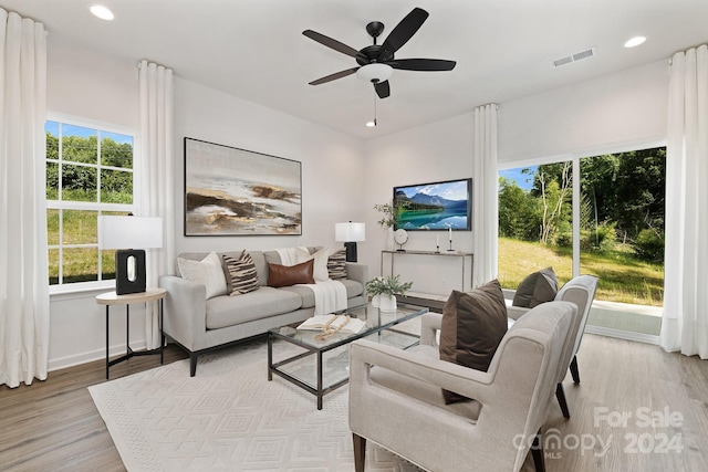 living room with light wood-type flooring, a wealth of natural light, and ceiling fan