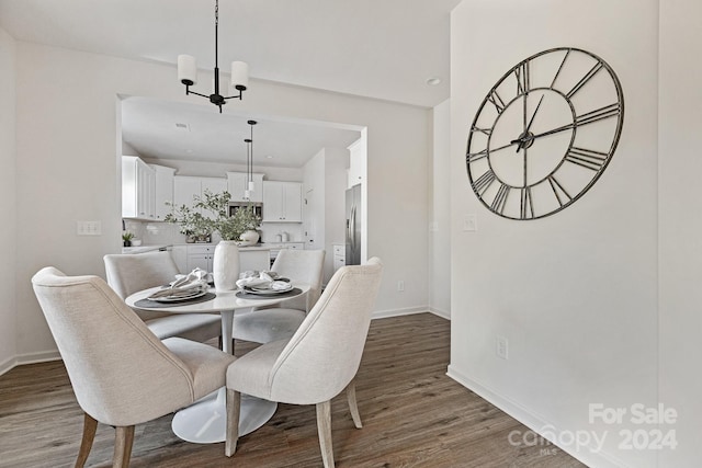 dining space with dark wood-type flooring and an inviting chandelier