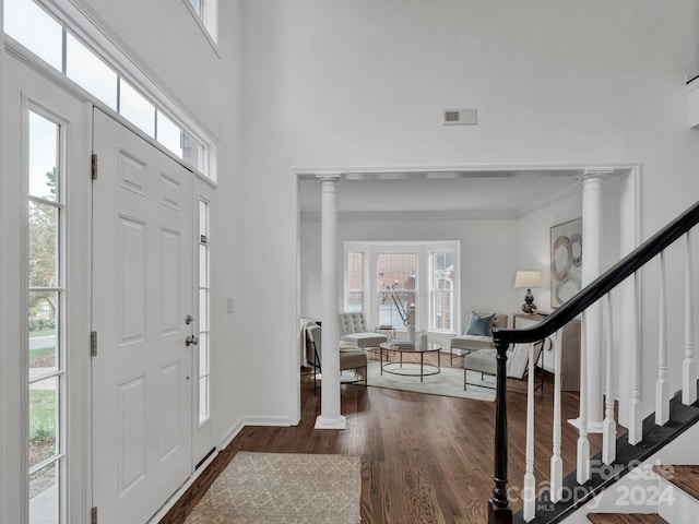 entrance foyer featuring ornate columns and dark wood-type flooring