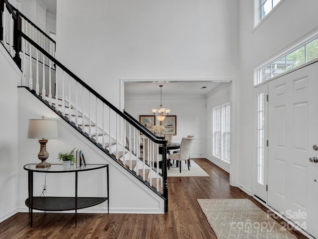 foyer entrance featuring dark hardwood / wood-style flooring, ornamental molding, a chandelier, and a high ceiling