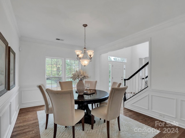 dining space featuring dark wood-type flooring, a chandelier, and crown molding