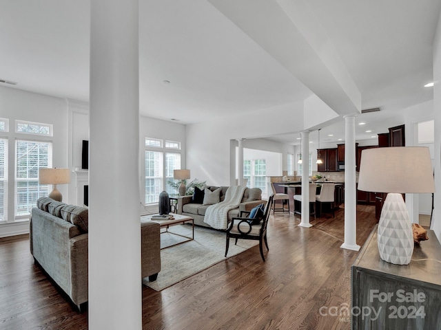 living room with dark hardwood / wood-style flooring and decorative columns