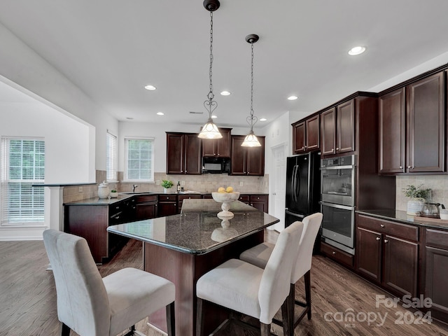 kitchen featuring black appliances, tasteful backsplash, dark hardwood / wood-style flooring, and hanging light fixtures