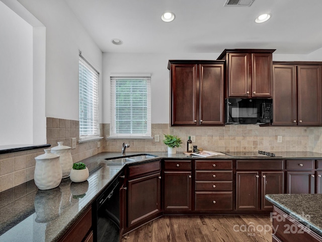 kitchen with hardwood / wood-style flooring, sink, black appliances, dark stone counters, and backsplash