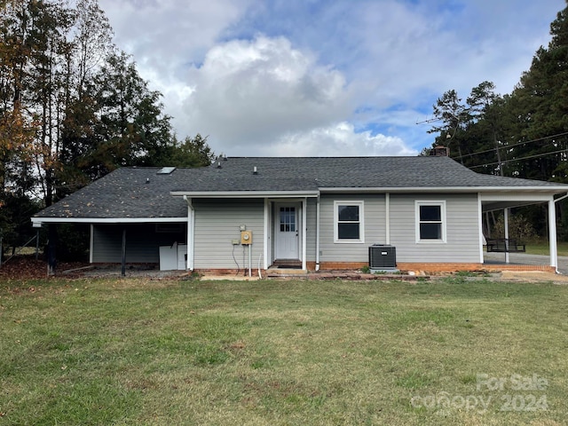 rear view of property with central AC, a carport, and a lawn