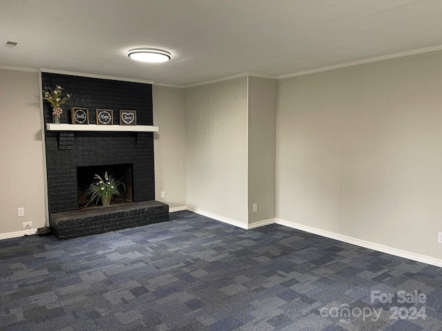 unfurnished living room featuring a brick fireplace, crown molding, and dark colored carpet