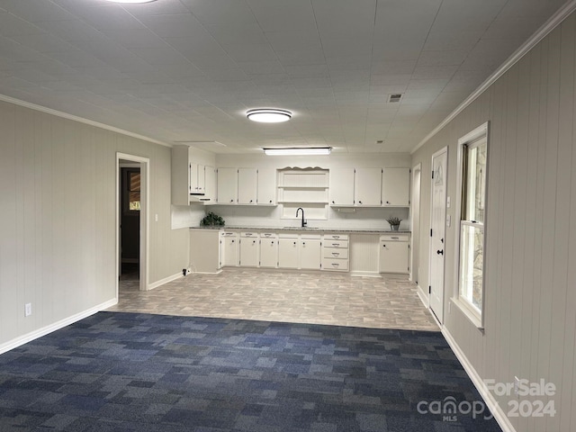 kitchen featuring dark carpet, white cabinets, crown molding, and sink