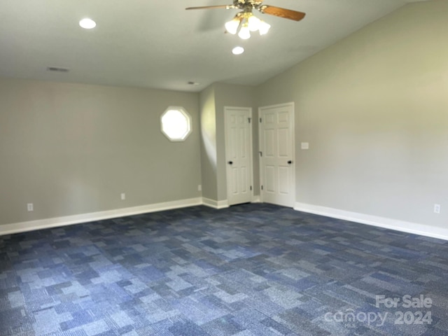 spare room featuring dark carpet, ceiling fan, and lofted ceiling