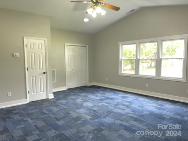 unfurnished bedroom with dark colored carpet, vaulted ceiling, and ceiling fan