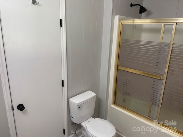 bathroom with toilet and bath / shower combo with glass door