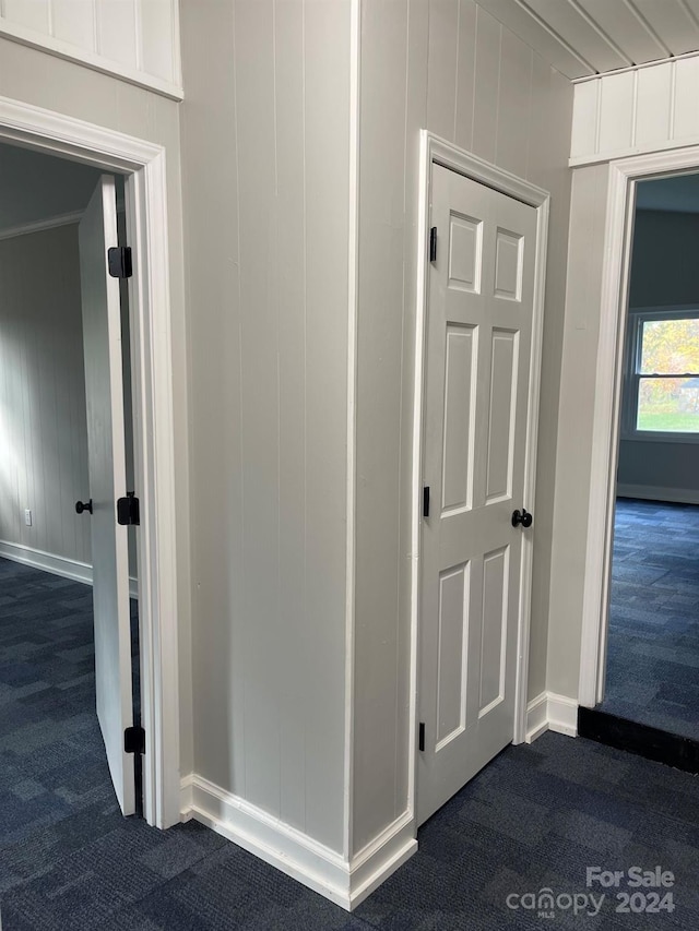 hall with dark carpet and wood walls