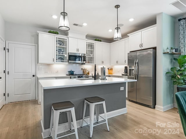 kitchen with light hardwood / wood-style floors, sink, appliances with stainless steel finishes, an island with sink, and decorative backsplash