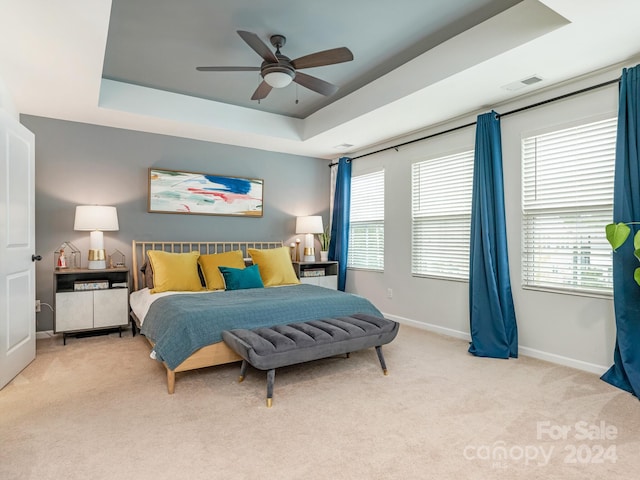 carpeted bedroom featuring ceiling fan and a raised ceiling