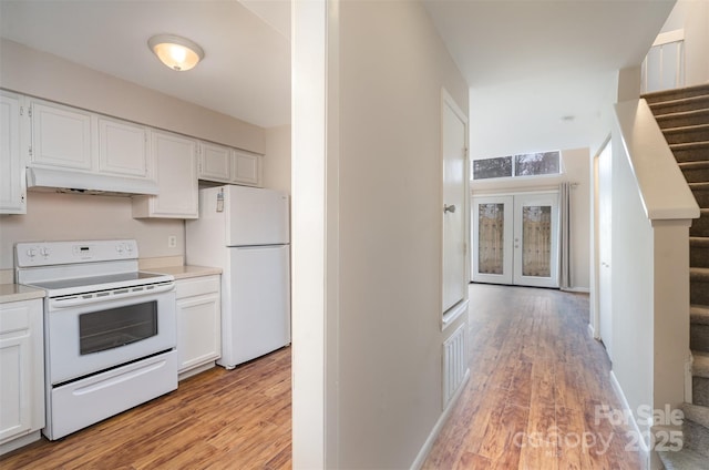 kitchen with light wood-type flooring, white cabinets, french doors, and white appliances