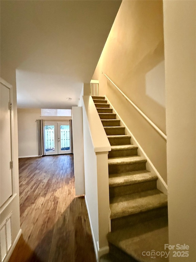 stairs featuring hardwood / wood-style floors and french doors