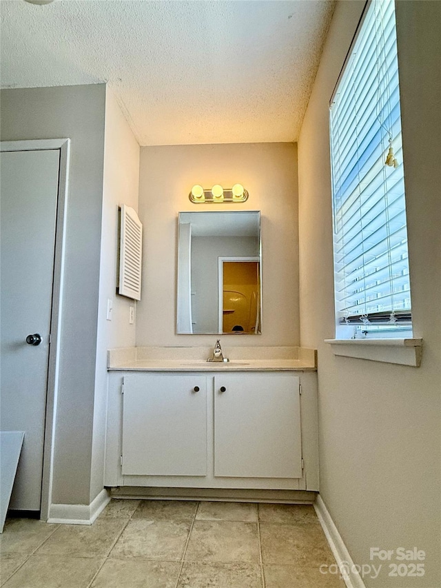 bathroom with a textured ceiling, tile patterned flooring, and vanity