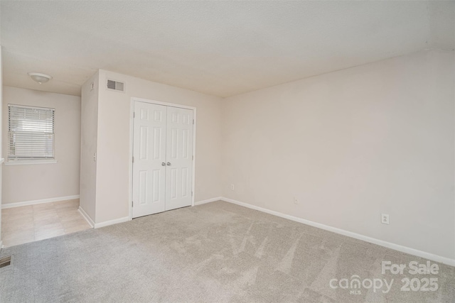 unfurnished bedroom with a closet and light carpet