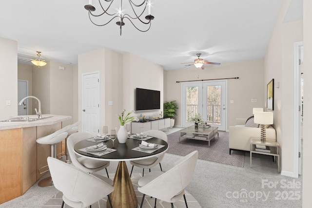 carpeted dining space featuring ceiling fan with notable chandelier and sink