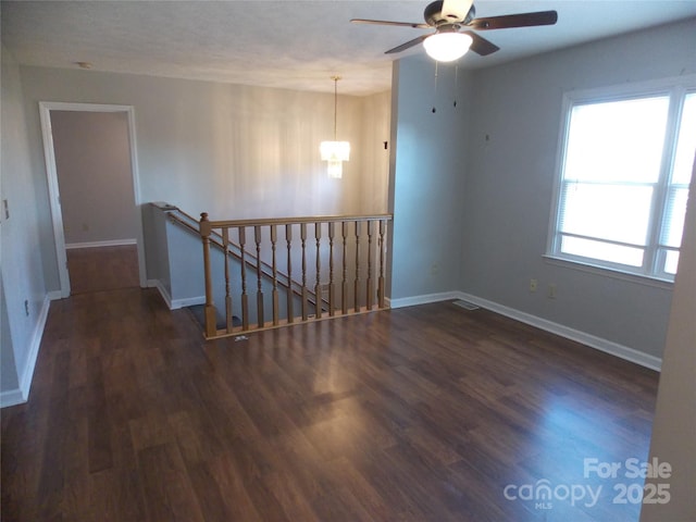 unfurnished room featuring ceiling fan with notable chandelier and dark hardwood / wood-style floors